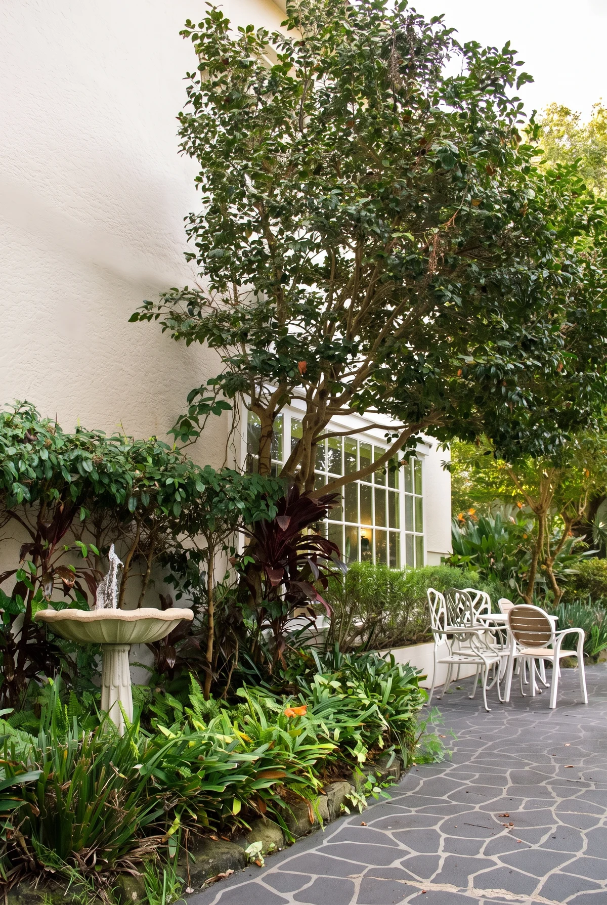 White iron chairs and a table in the garden courtyard beside the sunroom windows
