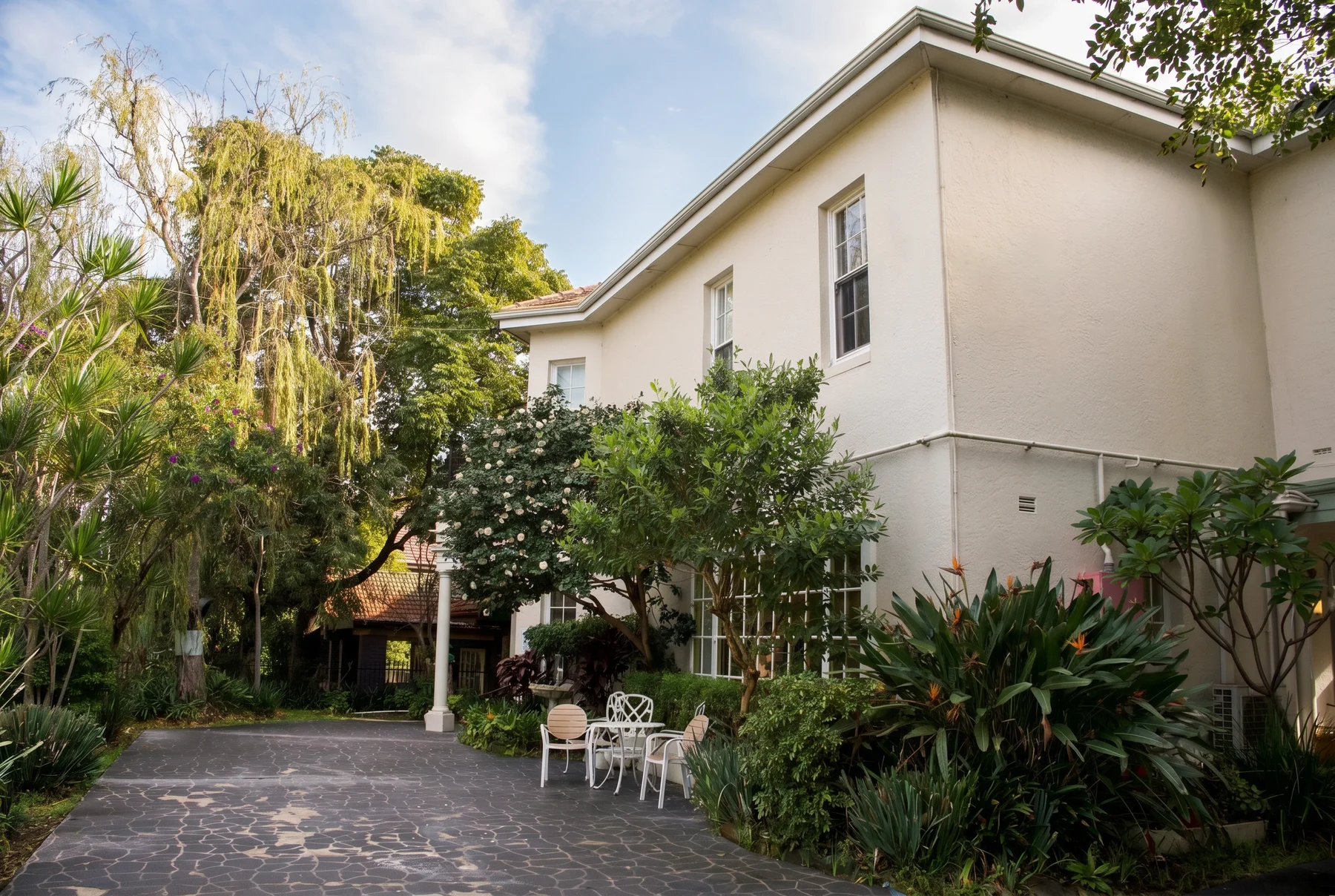 The Willows: the cream two-storey home behind its gardens in afternoon light